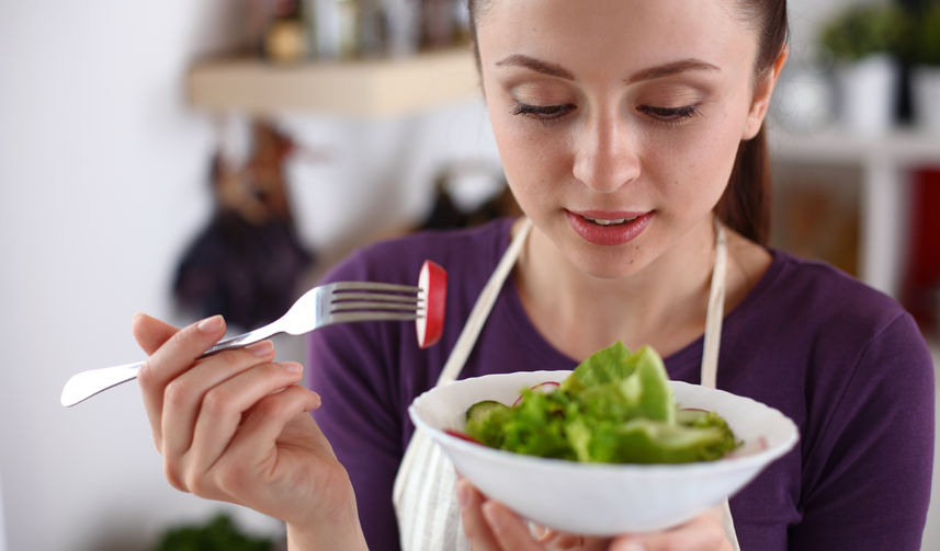 young woman eating green salad